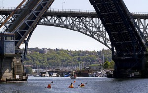 Ellen M. Banner / The Seattle Times  Kayakers head toward the Fremont Bridge, while the Aurora Bridge looms above it.